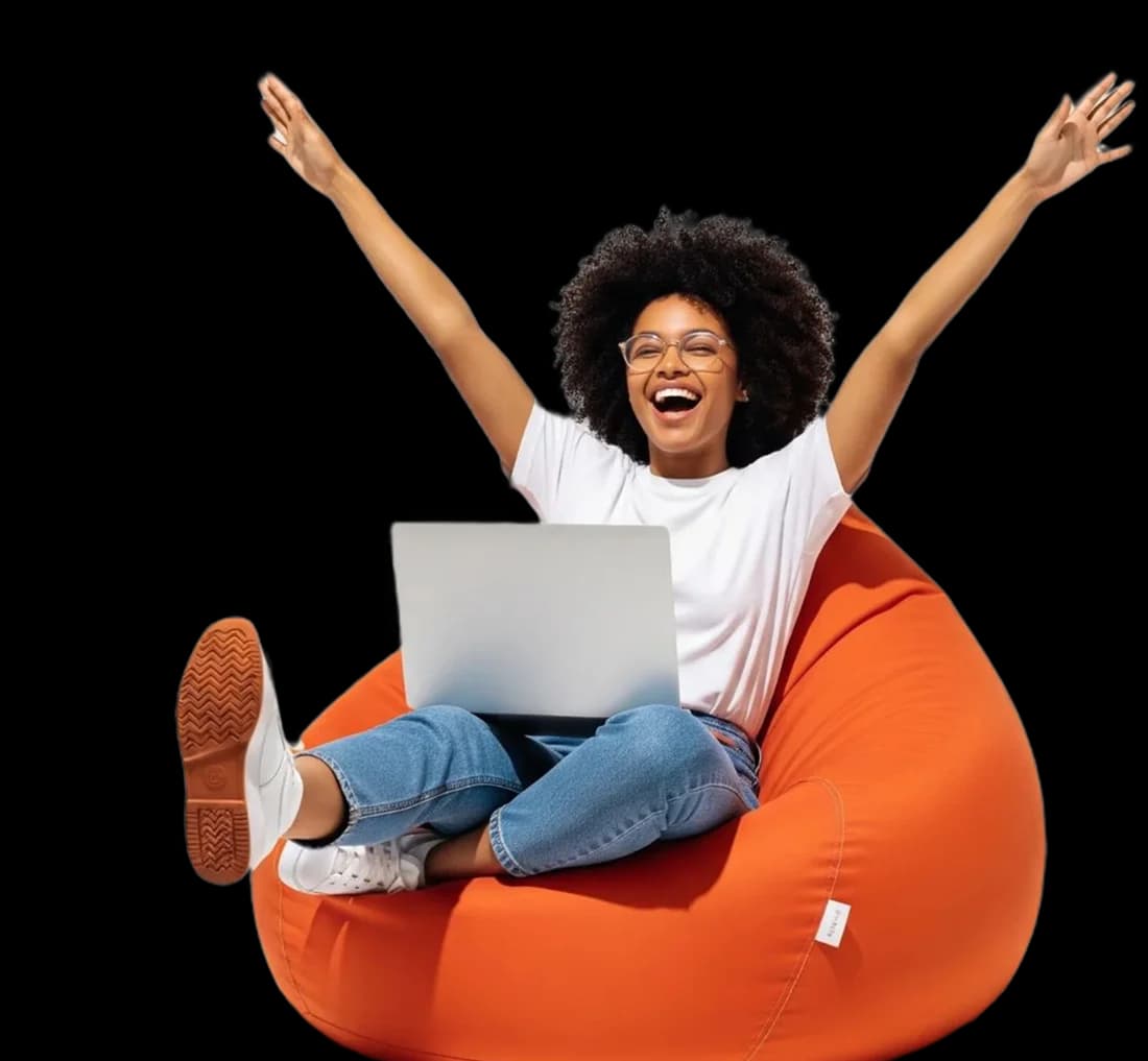 Happy shopper relaxing on a bean bag with a laptop, surrounded by bags, phones, laptops and clothes